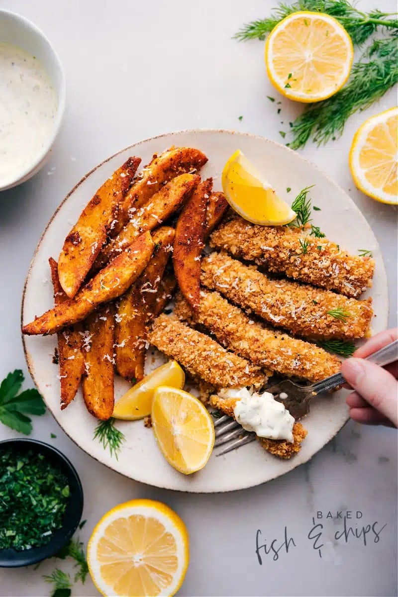 baked-fish-and-chips Baked breaded fish sticks with French fries served on plate with lemon wedge.