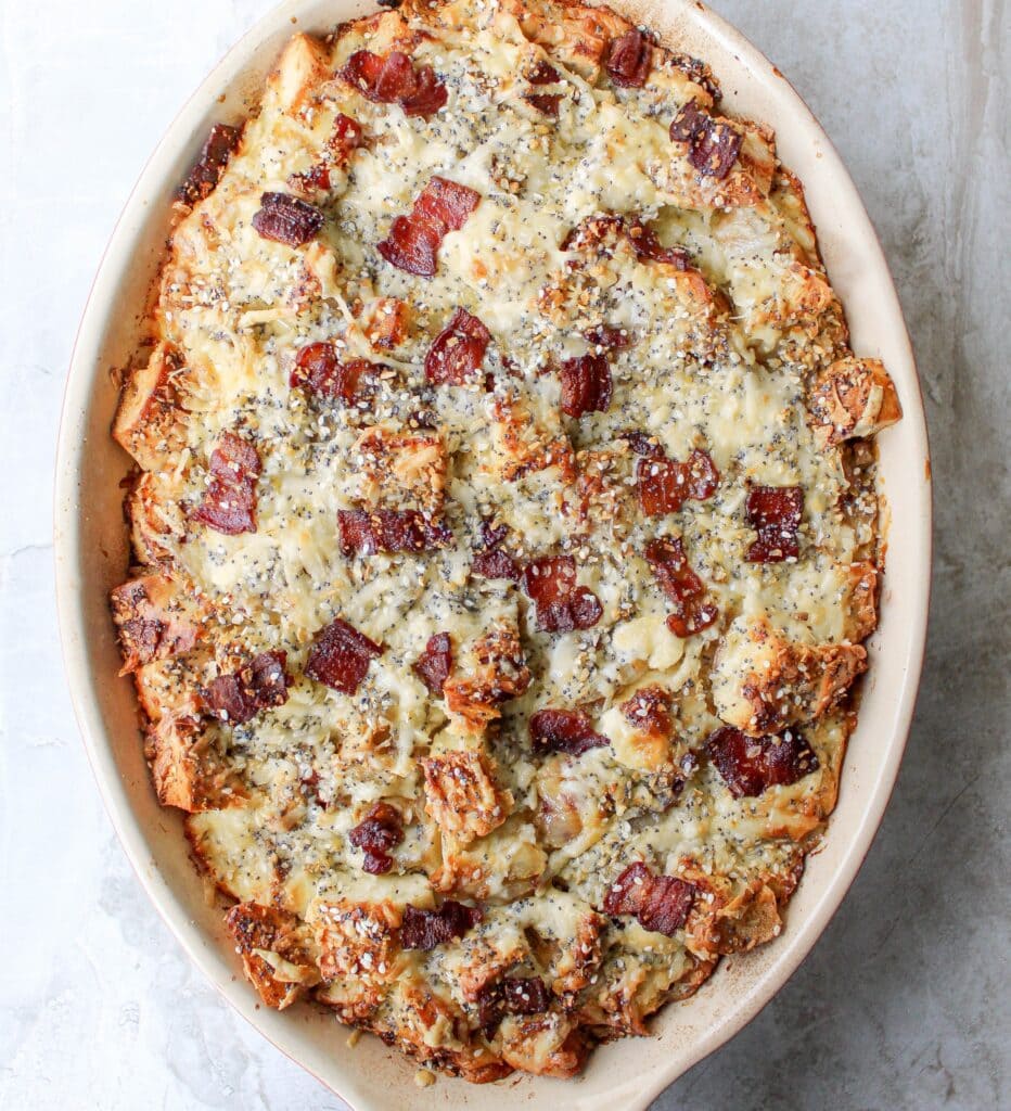 Breakfast sandwich strata made with bagels, crispy bacon, and cheese in a custardy casserole. 