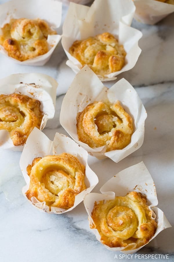 Mini pastry rolls wrapped with a paper cup arranged on top of a white marble table.