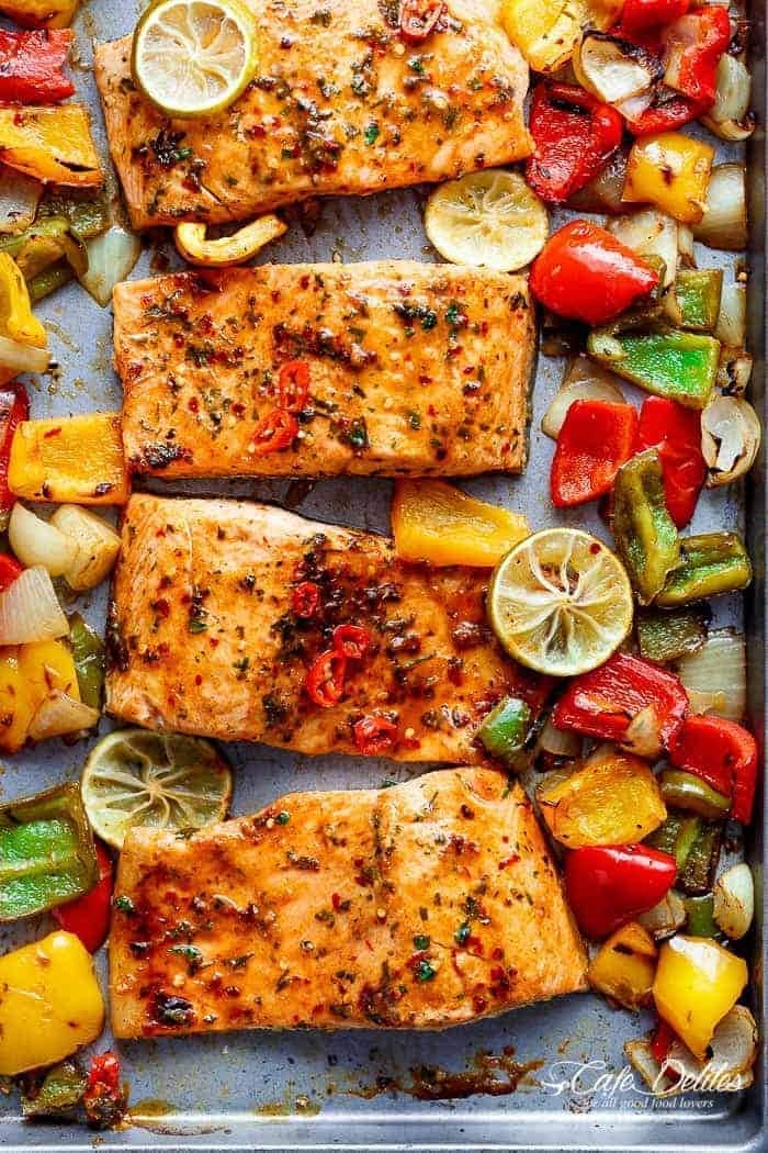 salmon-sheet-pan Salmon slices on sheet pan with onions and red, green, and yellow bell peppers.