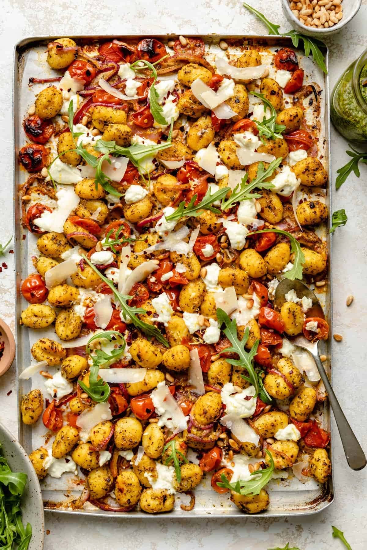 sheet-pan-pesto-gnocchi Pesto gnocchi with tomato, onions, and parmesan cheese cooked in a sheet pan.