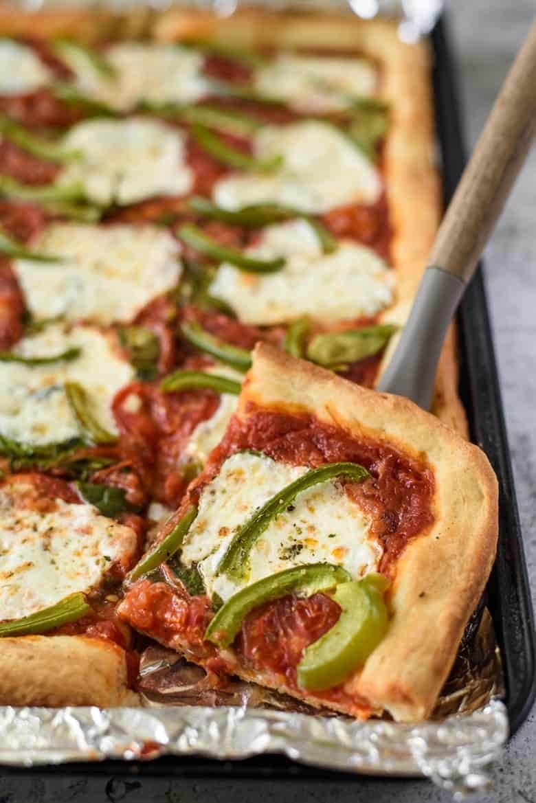 sheet-pan-pizza Sliced sheet pan pizza topped with cheese and bell pepper.