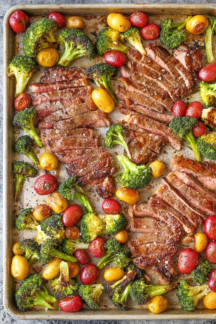 sheet-pan-steak-and-veggies Sliced steak cooked on a sheet pan with broccoli, potatoes and cherry tomatoes.