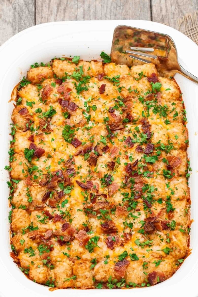 Cheesy tater tot breakfast casserole in a white dish.